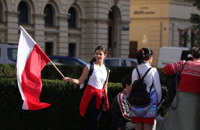 Uczennica z biało-czerwoną flagą przed gmachem na trasie, 2023